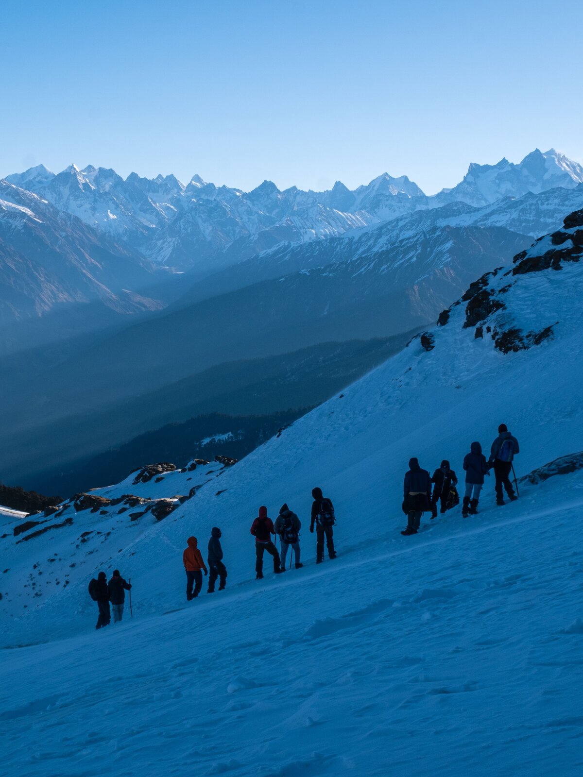 Trekkers descending Kedarkantha ridge at dusk