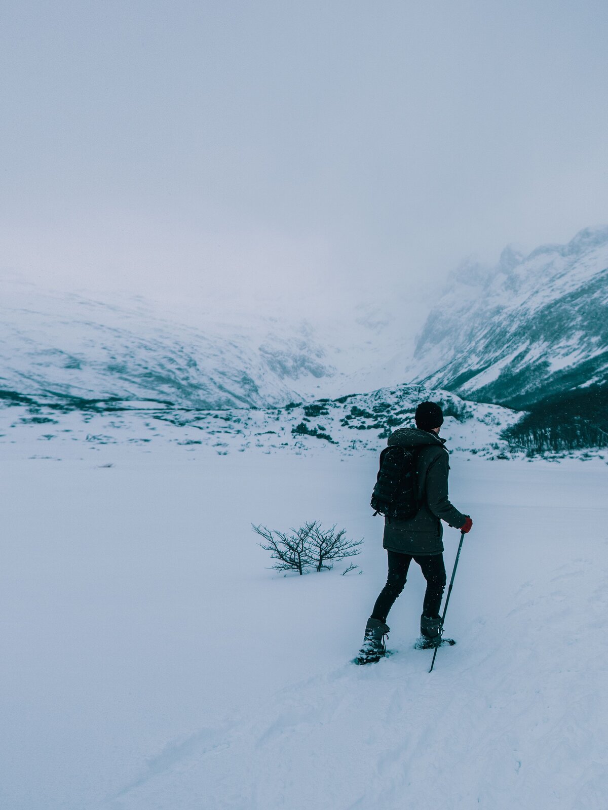 Solo trekker crossing a snowfield in fog
